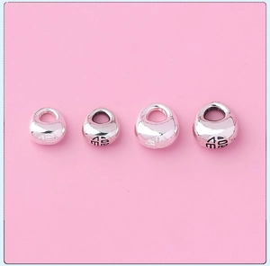 Detailed macro shot of four varied sizes of silver Fu character lucky charms for DIY jewelry