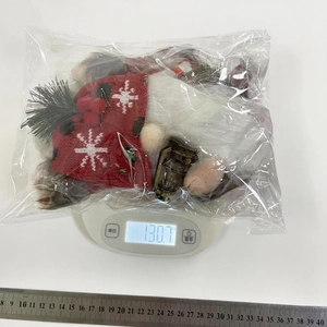 Detail shot of Christmas gnome plush with red snowflake hat and lantern on weighing scale