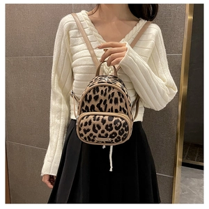 Close-up of leopard print mini backpack with metal plaque on the front pocket