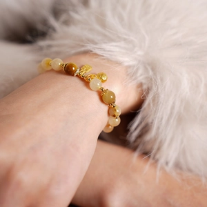 Détail d'un bracelet en citrine avec breloque dorée Fu sur fond de fourrure blanche