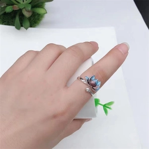 Adjustable silver koi ring with enamel lotus flower worn on hand with plant background