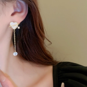 Detail of heart fringe earrings with gold-plated star rings and zircon tassels