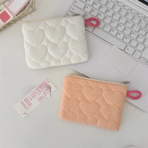 Detailed view of quilted heart pattern pouches in cream and peach pink fabric with zippers