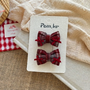 Close-up of red and grey plaid bow hair clips for kids on a white display card