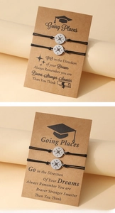 Detail of two black woven compass bracelets on a graduation card with inspirational quote