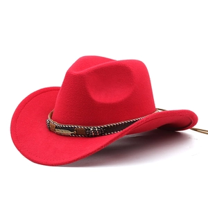 Detail of red cowboy hat with brown band featuring colorful beads and metal feather charm