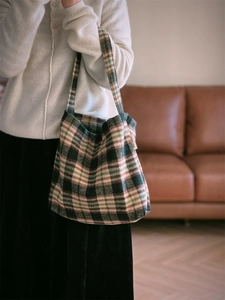 Détail du sac cabas vintage en laine à carreaux avec étiquette porté par un mannequin