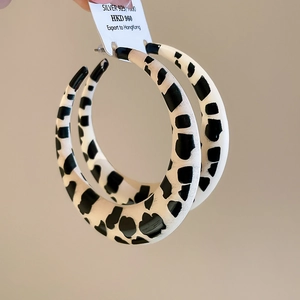 Macro view of chunky 925 silver hoop earrings featuring bold leopard pattern texture