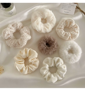 Close-up of 7 plush scrunchies in fleece, faux fur, and corduroy on white silk