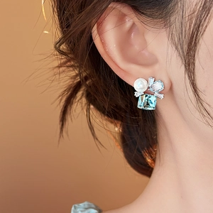 Eleganti orecchini geometrici in zircone blu con accento di perla indossati da una modella
