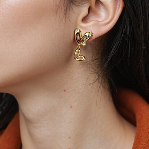 Golden double heart stud earrings with black enamel inlay and sparkling diamond accents