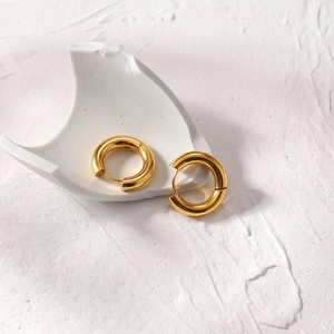 Detailed shot of 4mm thick gold stainless steel hoop earrings on a ceramic display