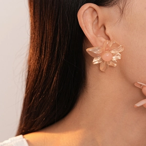 Detail of a model wearing a translucent pink resin flower earring with a beaded center