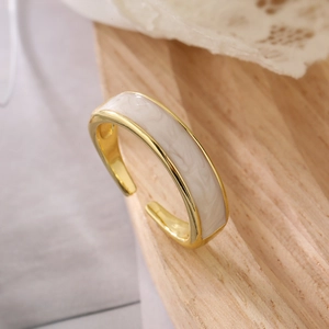 Detailed shot of an adjustable gold geometric ring with a white marble inlay on wood