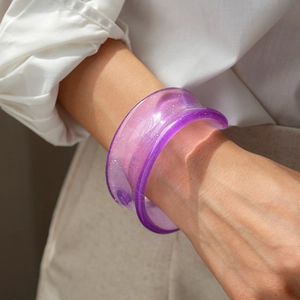 Detail of purple resin glitter bangle shown on wrist with a minimalist white shirt