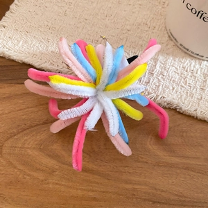 Close-up of colorful fuzzy twist rod firework hair clip on a textured wooden desk