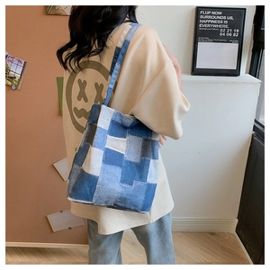 Detail view of a blue patchwork denim tote bag with long straps worn in a lifestyle setting