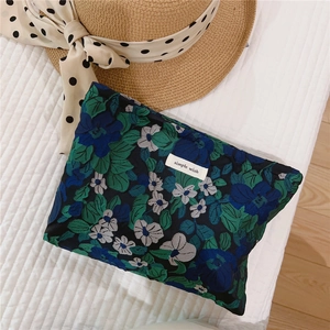 Close-up of blue and green floral jacquard makeup bag with simple wish label