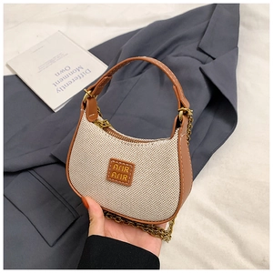 Détail d'un mini sac à main tissé beige avec bordure en cuir marron et chaîne en métal