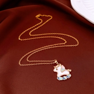 Golden unicorn pendant necklace with colorful enamel detailing on dark red fabric background