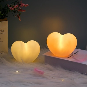 Detail of two heart-shaped night lights glowing in warm tones on a cozy white rug