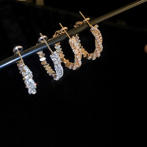 Macro shot of silver and gold hoop earrings with sparkling zircon stones and scale texture