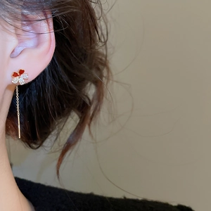 Detail of clover tassel earrings featuring gold plating, red enamel, and sparkling zirconia