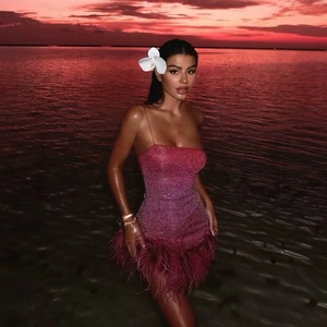 Robe moulante à paillettes dégradé rose avec plumes sur fond de plage au coucher