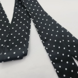 Primer plano de un pañuelo fino negro con lunares blancos y textura de tela delicada