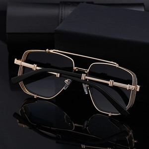 Close-up of gold metal frame sunglasses with double bridge and black lenses on black surface