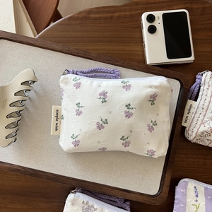 Detailed close-up of a floral mini coin purse with woven handle and simple wish label