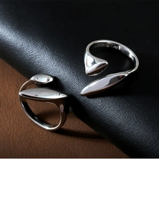 Macro detail of minimalist silver open rings with polished leaf design on leather