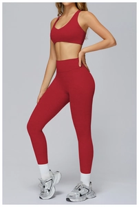 Side view of dark red high waist yoga leggings and racerback sports bra on a model