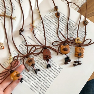 Macro shot of bear and star wooden pendants with brown cords on vintage book background