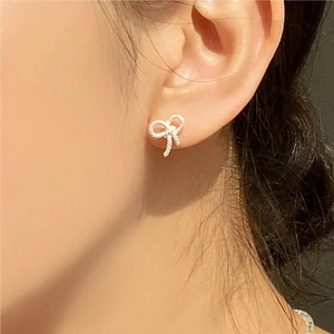 925 sterling silver bow stud earring with woven texture shown on a female earlobe