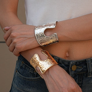 Wide gold and silver metallic cuff bracelets with hollow bark texture on model