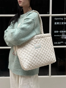 Quilted cream tote bag with blue logo tag, large capacity cotton shoulder bag on model
