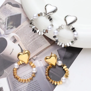 Detail view of heart-shaped hoop earrings with pearls in gold and silver finishes
