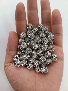 Close-up of hand holding 10mm silver Shamballa beads with crystal rhinestones for DIY
