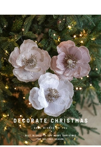 Pink and white fabric Christmas flowers with glitter on tree with warm lights