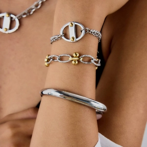 Close-up of stacked stainless steel bracelets and necklace with high polished finish