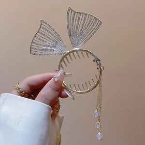 Detail of gold metal hair claw clip with rhinestones and elegant pearl tassels
