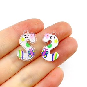 Close-up of white acrylic letter S pendant with colorful cartoon patterns for DIY jewelry