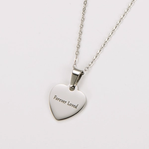 Macro shot of silver stainless steel heart pendant with Forever Loved engraving