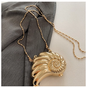 Detailansicht der goldenen Abendtasche in Schneckenform mit edler Perlenkette