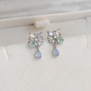 Macro shot of silver flower earrings with colorful marquise zircons and blue drop pendant