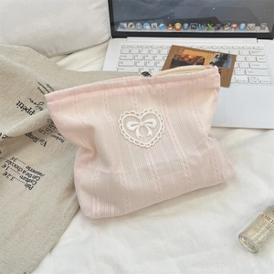 Detailed close-up of pink ribbon cosmetic bag with lace heart and bow on top
