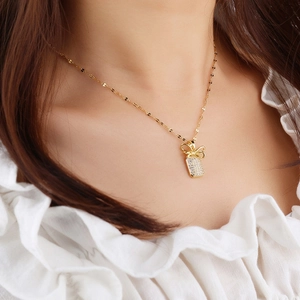 Elegant gold bow necklace with sparkling zircon pendant worn by a model on neck