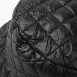 Detailed close-up of the black quilted diamond pattern and plush padded fabric texture