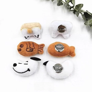 Detail of plush cartoon brooches showing front embroidery and rear metal pin attachment